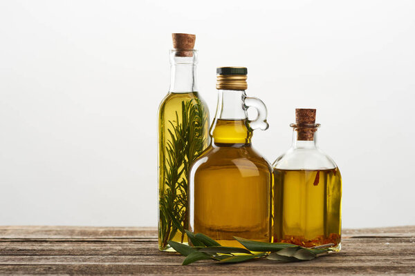 bottles of olive oil flavored with rosemary and spices isolated on grey 