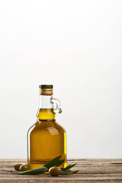 bottle of with olive tree leaves and olives  isolated on grey 