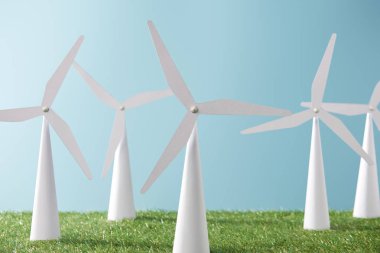 white windmill models on blue background and green grass   clipart