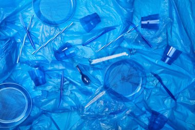 mavi buruşuk polietilen torba plastik şişe, bardak, tabak, bıçak, kaşık ang sünger ile üstten görünüm