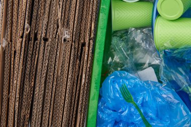 karton, buruşuk plastik torbalar, plastik bardak ve çatal çöpü üstten görünüm