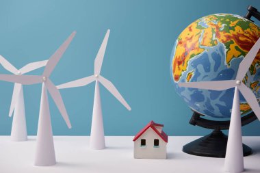 windmill and house models with globe on white table and blue background clipart