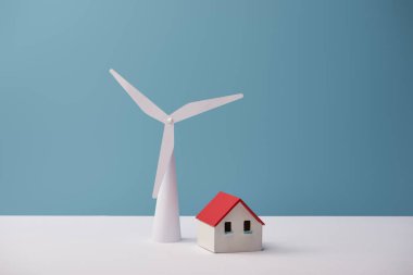 windmill and house models on white table and blue background clipart