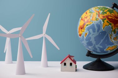 windmill and house models with big globe on white table and blue background clipart