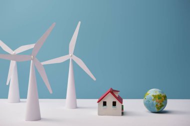 windmill and house models with small globe on white table and blue background clipart