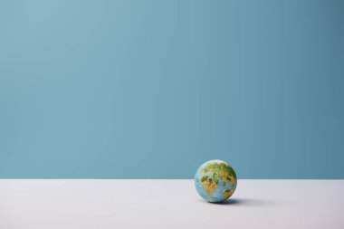 small globe on white table and blue background clipart