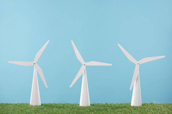 белые модели ветряной мельницы на траве и синем фоне
   