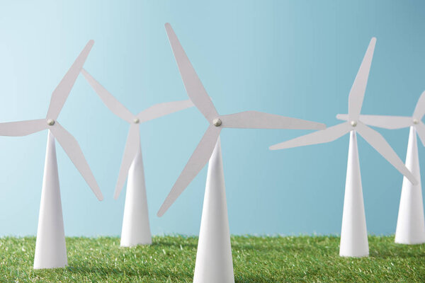 модели ветряной мельницы на синем фоне и зеленой траве
  