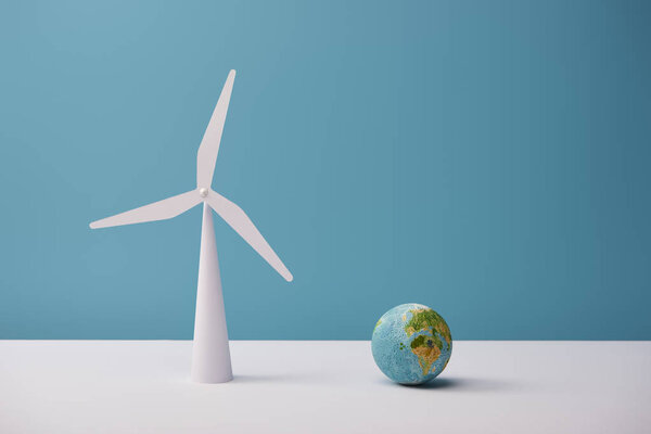 small globe and windmill model on white table and blue background