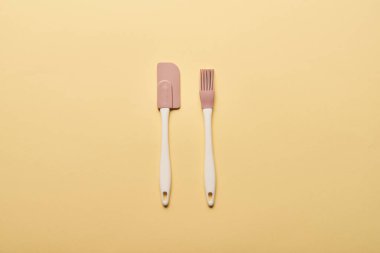 sarı zemin üzerine silikon spatula ve ekmek fırça üstten görünüm