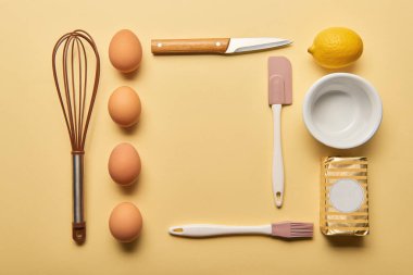 Mutfak eşyaları, limon, tereyağı ve yumurta sarı zemin üzerine pişirme ile düz lay