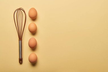sarı arka plan üzerinde Balon çırpıcı ve yumurta üstten görünüm