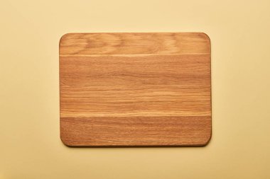 top view of empty wooden chopping board on yellow background  clipart