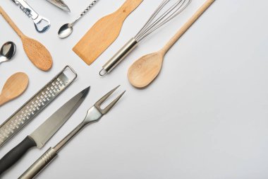 düz lay gri arka plan üzerinde metal ve ahşap mutfak aletleri ile 