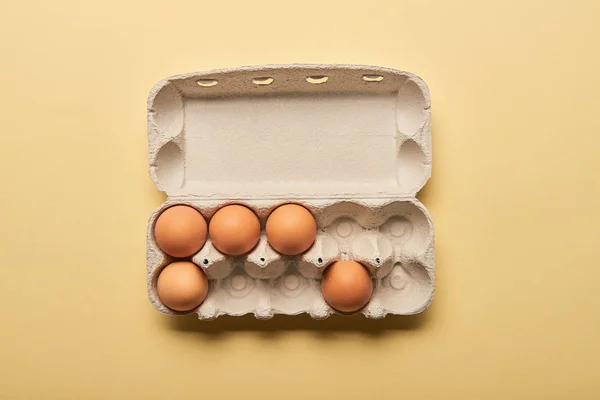 在黄色背景的纸板箱棕色有机蛋的顶视图 — 图库照片
