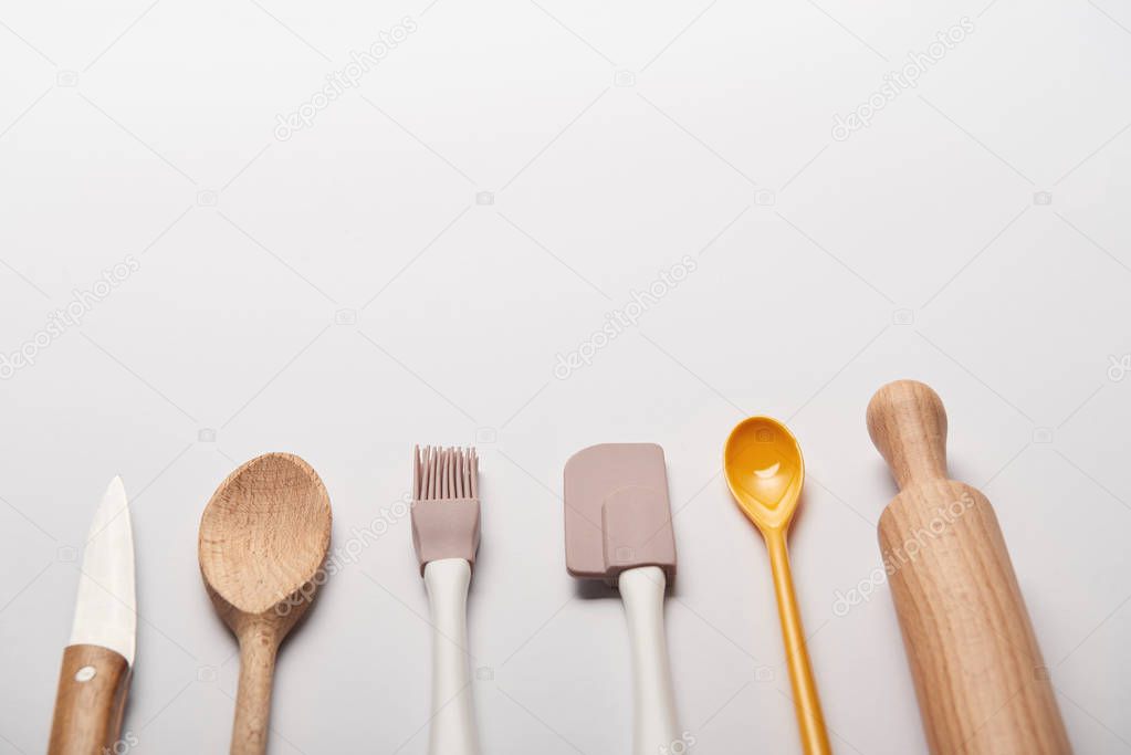 cooking utensils arranged in line on grey background with copy space