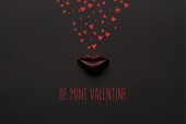Draufsicht auf leckere Schokoladenlippen auf schwarzem Hintergrund mit be mine valentine Schriftzug 