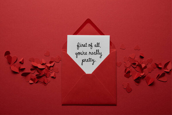 верхний вид конверта с надписью "Во-первых, вы действительно красивы", с вырезанными бумагой сердцами на красном фоне
 