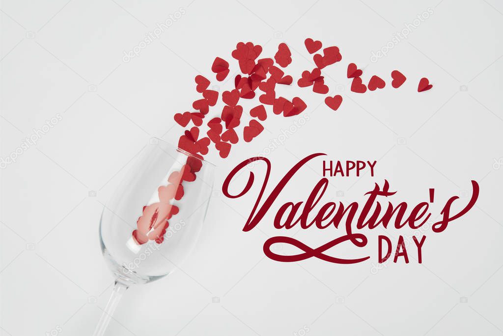 top view of wine glass and small paper cut hearts on white background with 