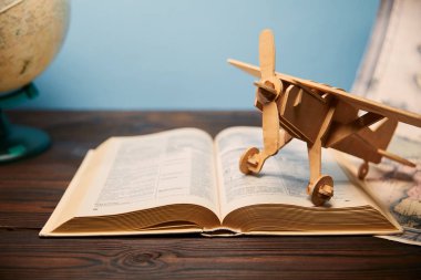 Selective focus of book and toy plane on wooden table clipart