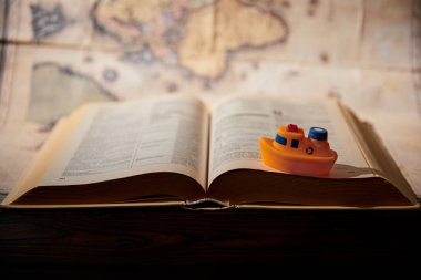 Selective focus of toy ship, book and map on table clipart