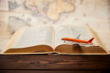 Selective focus of toy plane, book and map on wooden table clipart