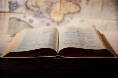 Selective focus of book and map on wooden table  clipart