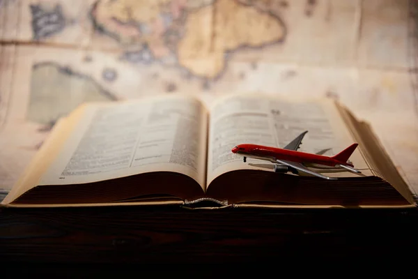 Selective focus of toy plane, book and map on table