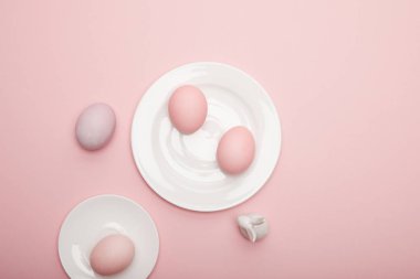 Oyuncak tavşan, uçan daire üzerinde boyalı Paskalya yumurtaları ve plaka pembe bir arka plan üzerinde Üstten Görünüm
