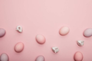 Pembe bir arka plan üzerinde oyuncak tavşanlar ve Paskalya yumurtaları Üstten Görünüm