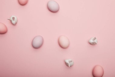 Pembe bir arka plan üzerinde oyuncak tavşanlar ve boyalı Paskalya yumurtaları Üstten Görünüm