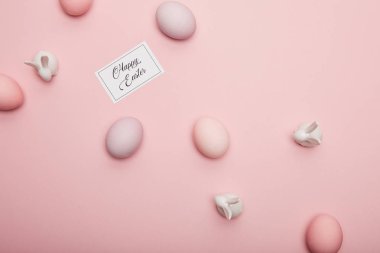Pembe bir arka plan üzerinde oyuncak tavşanlar, mutlu Paskalya yazı ve boyalı Paskalya yumurtaları kartı Üstten Görünüm