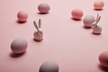 oyuncak tavşanlar ve kopya alanı ile pembe arka plan üzerine boyalı Paskalya yumurtaları 