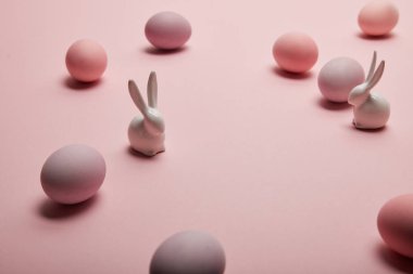 toy bunnies and painted easter eggs on pink background with copy space  clipart