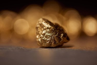 selective focus of golden stone on grey marble and blurred sparkling background clipart