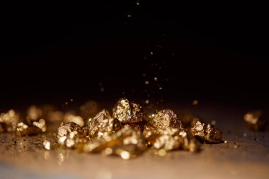 selective focus of golden stones on brown marble surface with blurred black background clipart