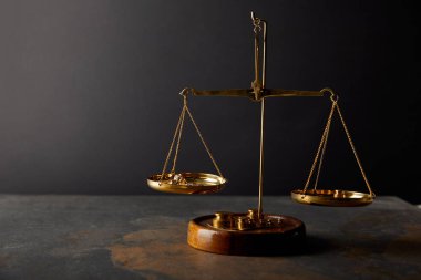 golden stones on scales on marble table and dark background clipart