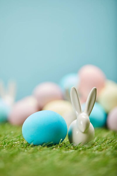selective focus of painted easter eggs and toy rabbit on grass with copy space 
