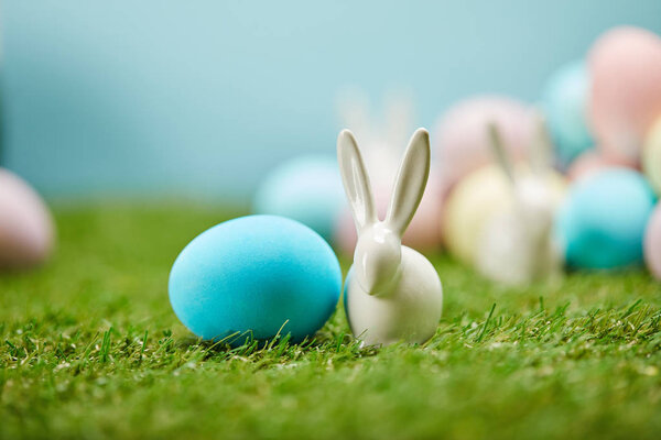 selective focus of painted easter eggs and toy rabbits on grass with copy space 