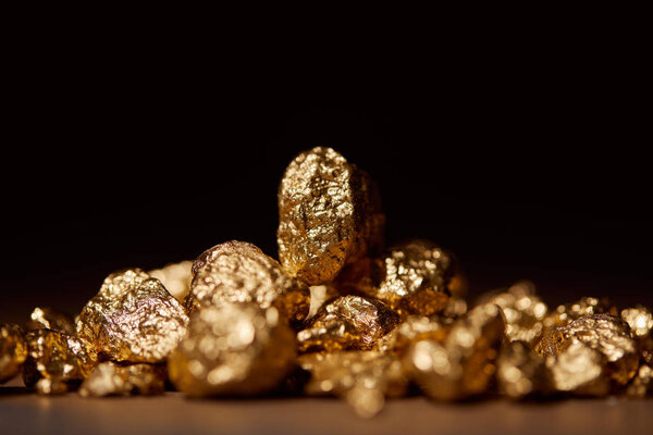 selective focus of golden stones on marble isolated on black