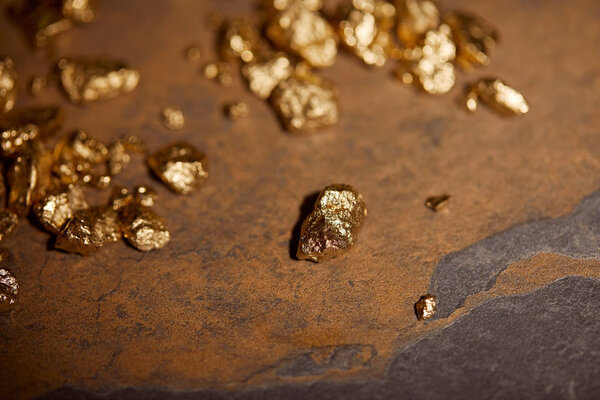 selective focus of golden stones on grey and brown marble surface