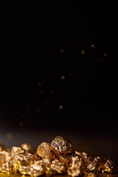 golden stones on dark surface with sparkling lights on black background