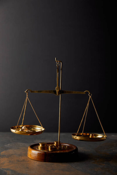 vintage scales with golden stones on marble surface and black background
