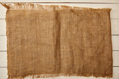 piece of brown sackcloth on white wooden surface clipart