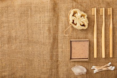 top view of different hygiene and care items on brown sackcloth surface, zero waste concept clipart