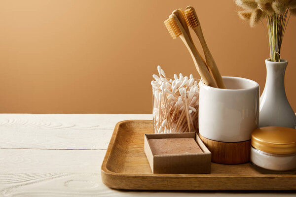 wooden tray with different hygiene and care items and vase of spikelets on white wooden surface, zero waste concept
