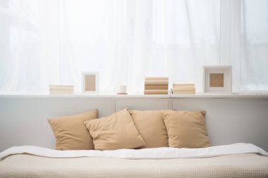 bedroom with brown pillows on bed, books, coffee cup and photo frames  clipart