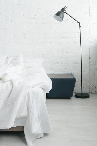 Bed with white sheets and blanket, lamp and black nightstand 