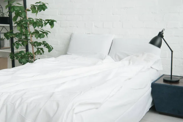 Κρεβάτι Άσπρη Κουβέρτα Και Μαξιλάρια Φυτών Και Λάμπα Στο Κομοδίνο — Φωτογραφία Αρχείου