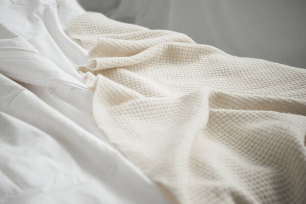 Close up of cozy empty bed with white blanket and sheets 